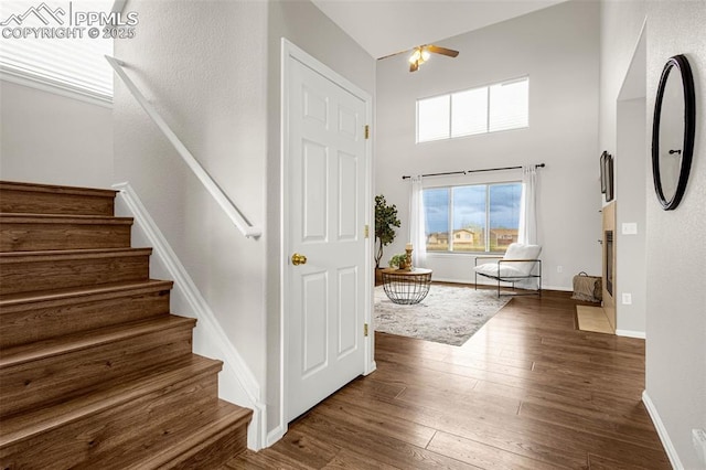 entryway featuring baseboards, ceiling fan, a high ceiling, dark wood-style floors, and stairway