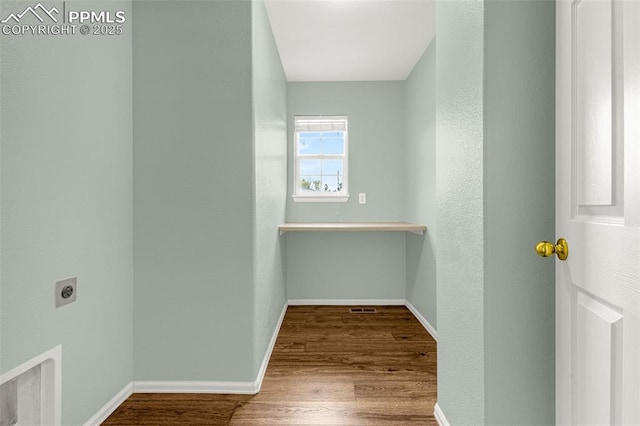 interior space with baseboards, hookup for an electric dryer, wood finished floors, and laundry area