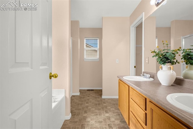 full bath featuring double vanity, a sink, baseboards, and a garden tub