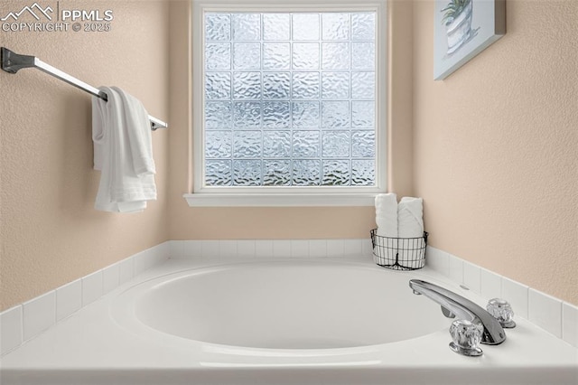 bathroom featuring a textured wall and a bath