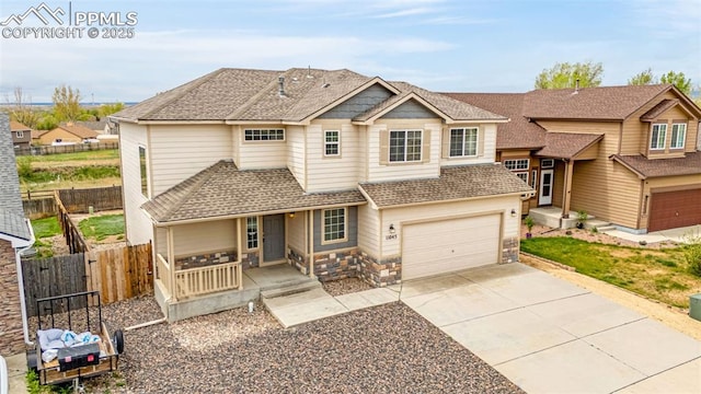 view of front of house with roof with shingles, fence, an attached garage, concrete driveway, and covered porch