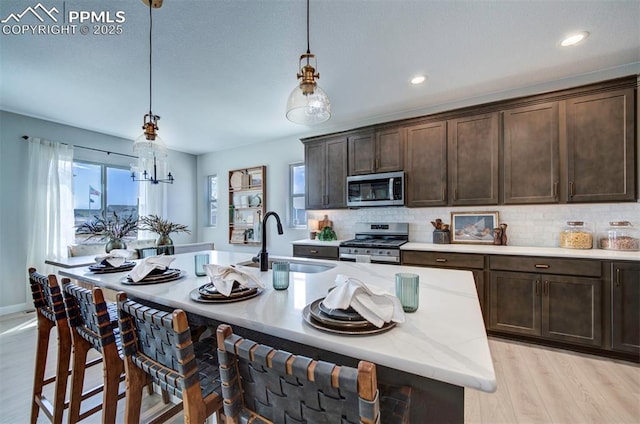 kitchen with a kitchen breakfast bar, appliances with stainless steel finishes, a sink, and dark brown cabinets