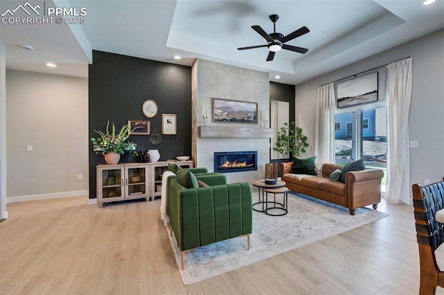 living area with baseboards, a ceiling fan, a tray ceiling, and recessed lighting