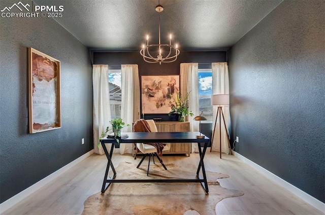 home office featuring a textured ceiling, wood finished floors, baseboards, a chandelier, and a textured wall