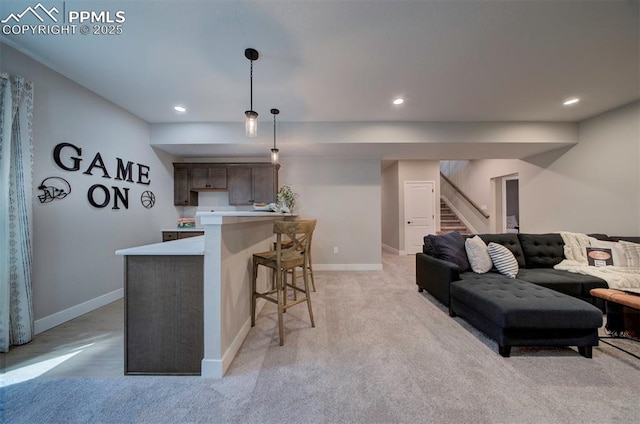 living room featuring baseboards, light colored carpet, bar area, and stairway