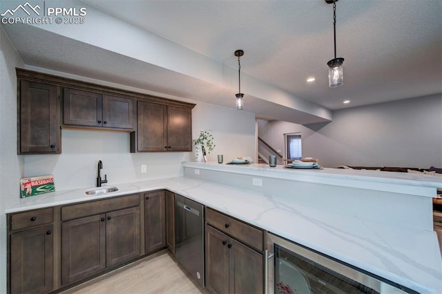 kitchen with stainless steel dishwasher, dark brown cabinets, light wood-type flooring, a sink, and decorative light fixtures