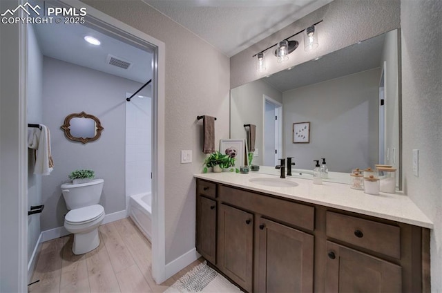 bathroom with visible vents, vanity, wood finished floors, toilet, and baseboards