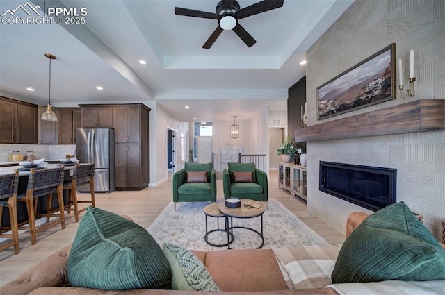 living room featuring ceiling fan, recessed lighting, baseboards, light wood-type flooring, and a tile fireplace