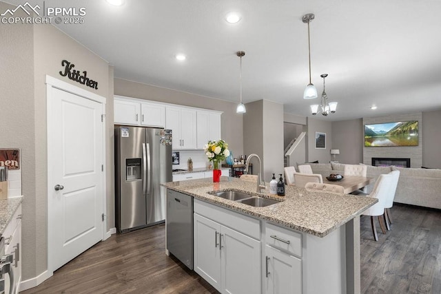 2186 Prairie Smoke Dr, Monument, CO 80132 - kitchen with hanging light fixtures, a sink, a fireplace, stainless steel appliances, and dark wood-style floors