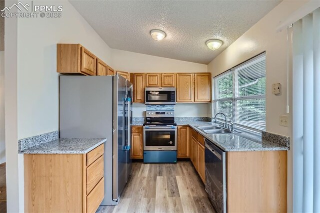 2903 E Serendipity Cir, Colorado Springs, CO 80917 - kitchen with stainless steel appliances, a textured ceiling, a sink, light wood-style floors, and vaulted ceiling