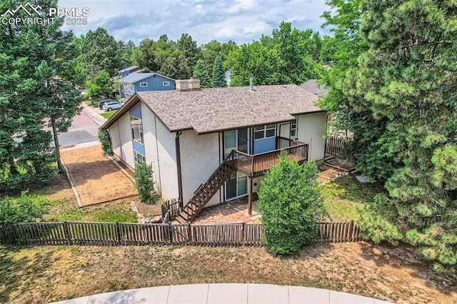 2903 E Serendipity Cir, Colorado Springs, CO 80917 - view of front facade with stucco siding, a fenced backyard, stairway, a deck, and a shingled roof