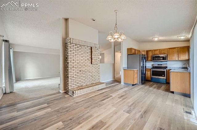 2903 E Serendipity Cir, Colorado Springs, CO 80917 - kitchen featuring appliances with stainless steel finishes, light wood-style floors, a textured ceiling, brown cabinets, and a sink