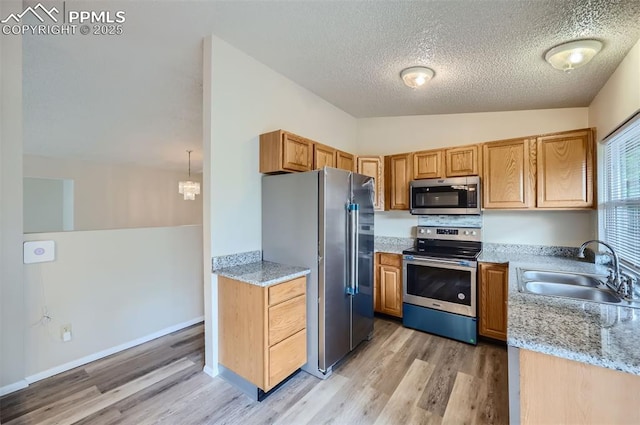 2903 E Serendipity Cir, Colorado Springs, CO 80917 - kitchen with appliances with stainless steel finishes, a sink, light wood-style floors, light stone counters, and a textured ceiling