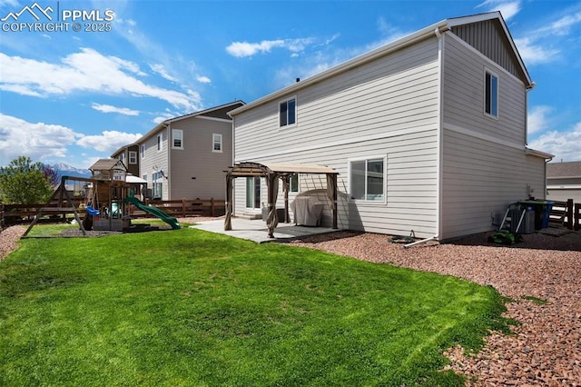 back of house with fence, a playground, board and batten siding, a patio area, and a lawn