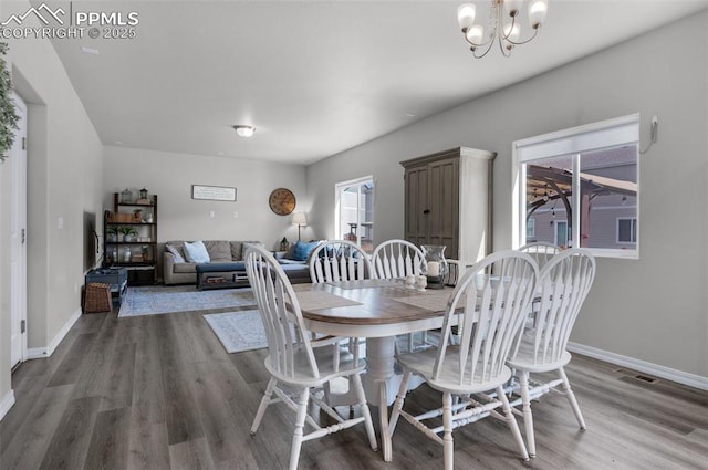 dining space featuring baseboards, a notable chandelier, wood finished floors, and visible vents