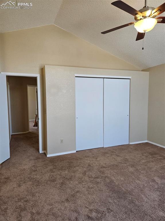 9367 Peaceful Meadow St, Colorado Springs, CO 80925 - unfurnished bedroom featuring lofted ceiling, a textured ceiling, carpet flooring, a closet, and baseboards