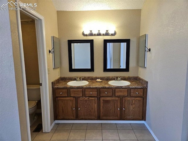 9367 Peaceful Meadow St, Colorado Springs, CO 80925 - bathroom with tile patterned flooring, toilet, double vanity, a textured wall, and baseboards