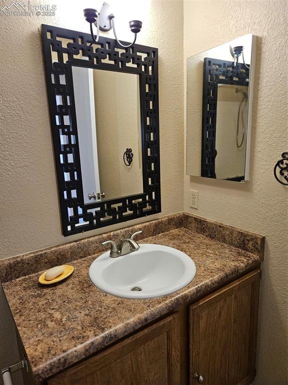 9367 Peaceful Meadow St, Colorado Springs, CO 80925 - bathroom featuring vanity, a textured wall, and a chandelier