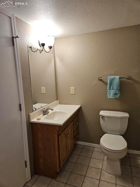 9367 Peaceful Meadow St, Colorado Springs, CO 80925 - half bath with vanity, toilet, a textured ceiling, tile patterned flooring, and baseboards