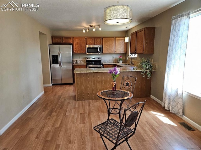 9367 Peaceful Meadow St, Colorado Springs, CO 80925 - kitchen with appliances with stainless steel finishes, brown cabinetry, and light wood-style floors