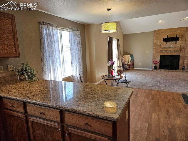 9367 Peaceful Meadow St, Colorado Springs, CO 80925 - kitchen with a peninsula, decorative light fixtures, light wood-style flooring, a brick fireplace, and open floor plan