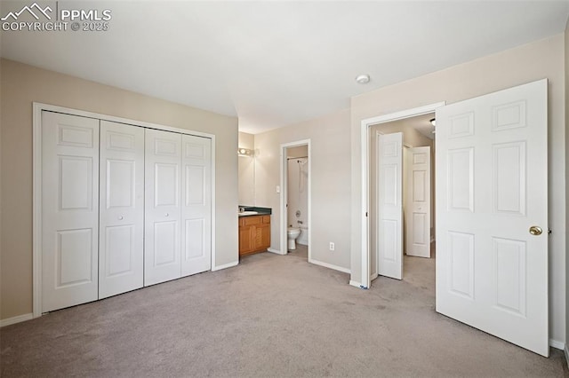 unfurnished bedroom featuring baseboards, ensuite bath, light carpet, and a closet