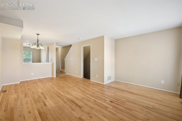 unfurnished living room with light wood-style floors, baseboards, a chandelier, and visible vents