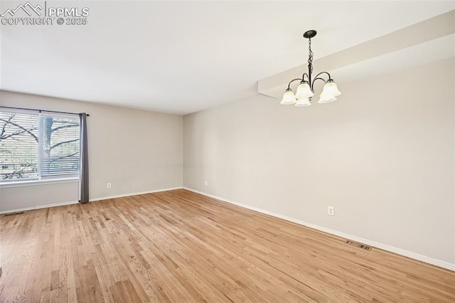 unfurnished room with an inviting chandelier, baseboards, light wood finished floors, and visible vents