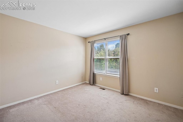 spare room with light colored carpet, baseboards, and visible vents