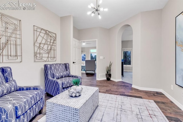 living area featuring visible vents, wood finished floors, baseboards, arched walkways, and a notable chandelier