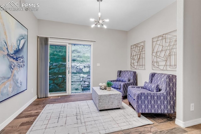 living area with an inviting chandelier, baseboards, and wood finished floors