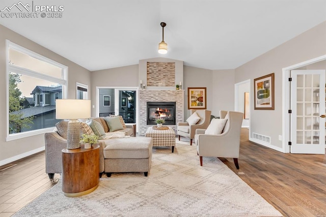 living room with a glass covered fireplace, baseboards, wood finished floors, and visible vents