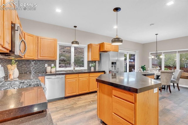 kitchen featuring a sink, light wood-style flooring, dark countertops, and stainless steel appliances
