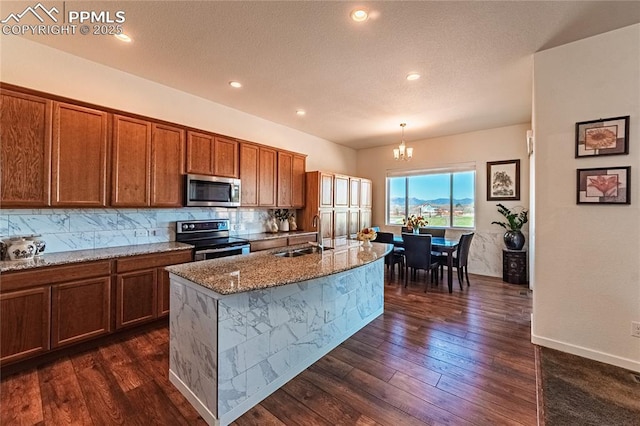 kitchen featuring a sink, an inviting chandelier, stainless steel appliances, and brown cabinets