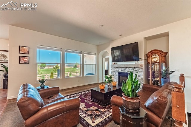 living room with carpet, a fireplace, baseboards, and arched walkways