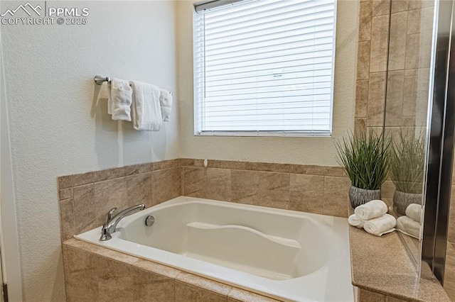 bathroom featuring a textured wall and a bath