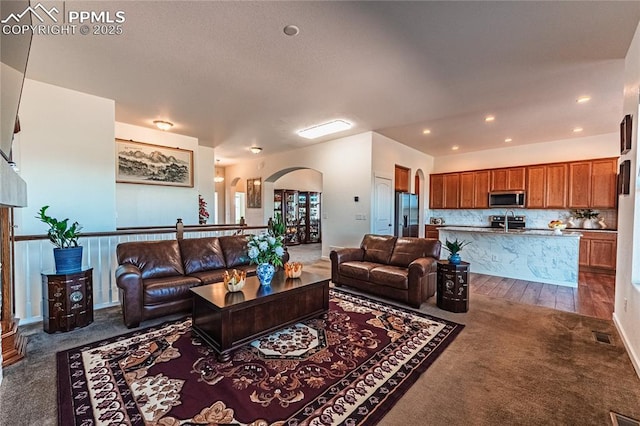 living room with arched walkways, visible vents, dark colored carpet, and recessed lighting
