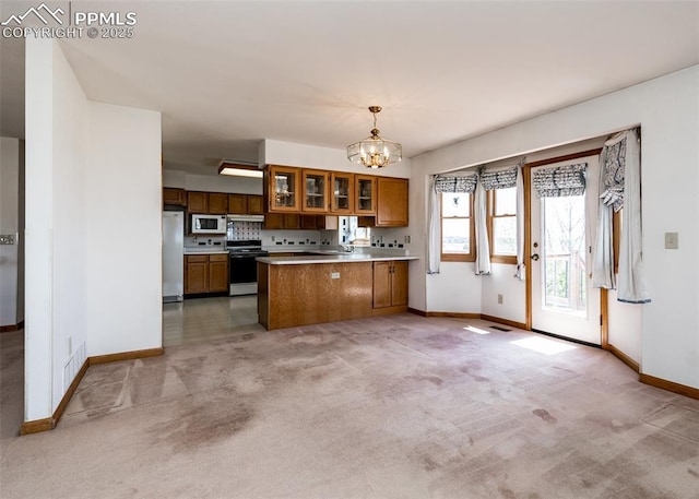 6185 Sayres Rd, Colorado Springs, CO 80927 - kitchen with brown cabinetry, freestanding refrigerator, white microwave, a peninsula, and electric stove