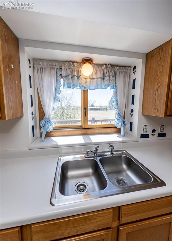 6185 Sayres Rd, Colorado Springs, CO 80927 - kitchen with brown cabinetry, a sink, a healthy amount of sunlight, and light countertops