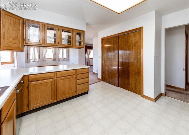 6185 Sayres Rd, Colorado Springs, CO 80927 - kitchen featuring light countertops, brown cabinetry, glass insert cabinets, and light floors