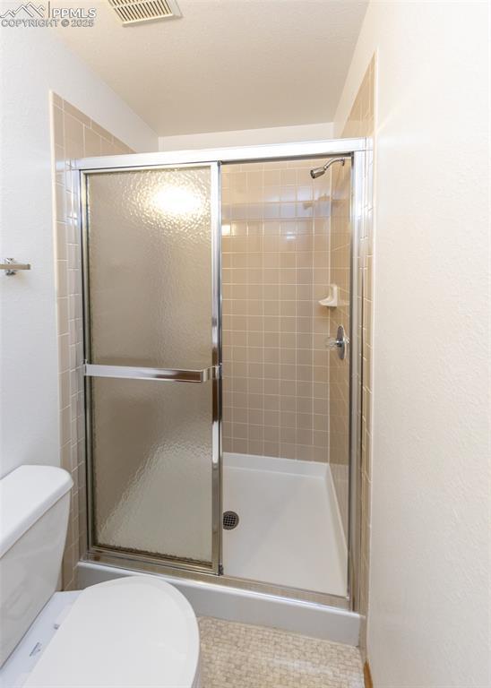 6185 Sayres Rd, Colorado Springs, CO 80927 - bathroom with a stall shower, toilet, and visible vents