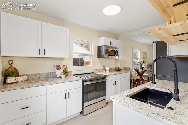kitchen with stainless steel appliances, a wealth of natural light, a sink, and white cabinetry