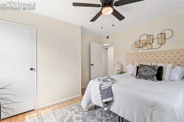 bedroom featuring visible vents, crown molding, wood finished floors, baseboards, and a ceiling fan