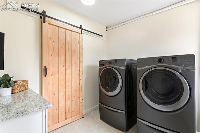 laundry room with light tile patterned floors, laundry area, a barn door, and washing machine and clothes dryer
