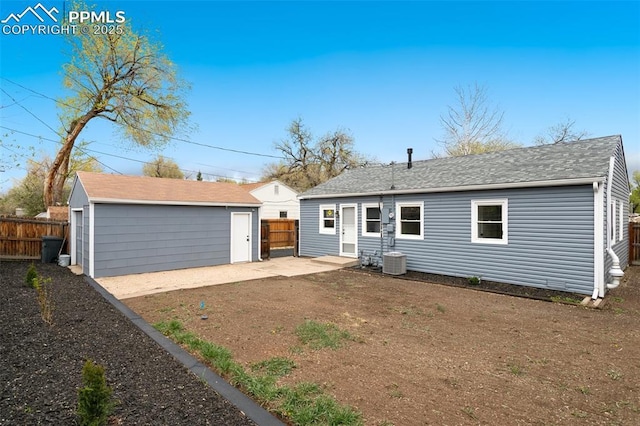 rear view of property featuring an outdoor structure, a shingled roof, fence, and a patio