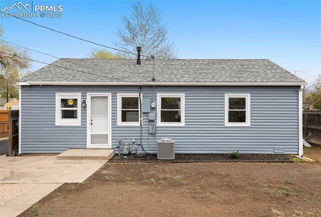 rear view of house with central AC, fence, a patio area, and roof with shingles