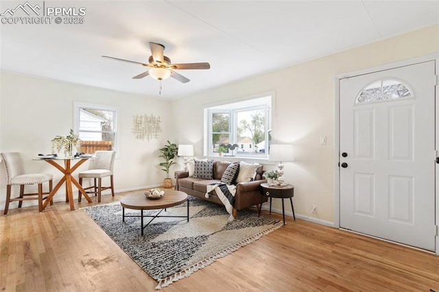 living room with a ceiling fan, baseboards, and light wood-type flooring
