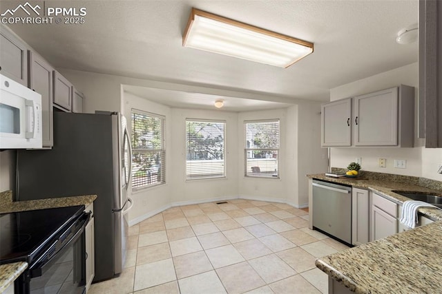 3245 Chestnut Glen Ln, Colorado Springs, CO 80918 - kitchen with dishwasher, white microwave, light stone counters, light tile patterned floors, and gray cabinets