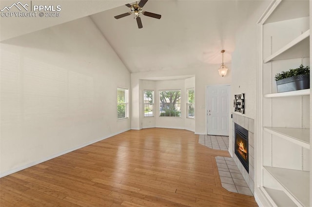 3245 Chestnut Glen Ln, Colorado Springs, CO 80918 - unfurnished living room with high vaulted ceiling, light wood-style floors, a tiled fireplace, and a ceiling fan