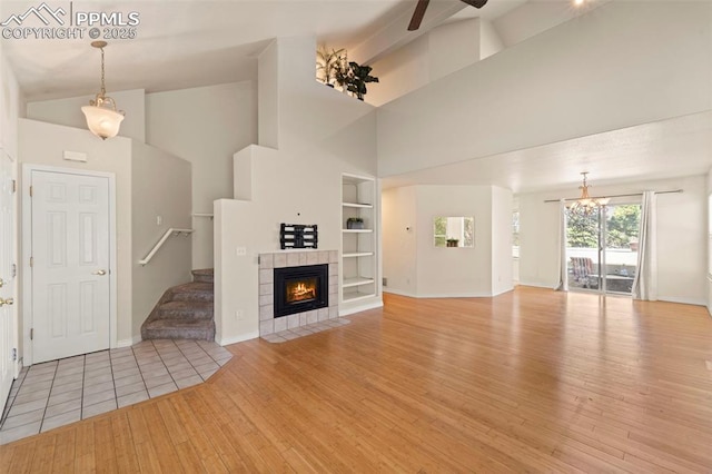 3245 Chestnut Glen Ln, Colorado Springs, CO 80918 - unfurnished living room featuring light wood finished floors, built in shelves, high vaulted ceiling, stairs, and a ceiling fan